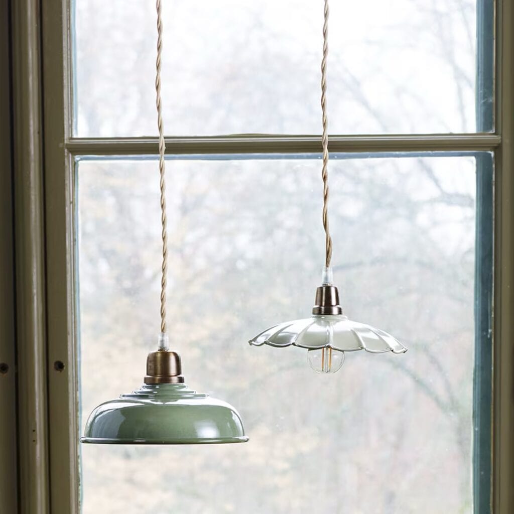 Taklampa Gustav Vit i vågigt glas och mässing hängande i köksfönster med grön växt och keramik.