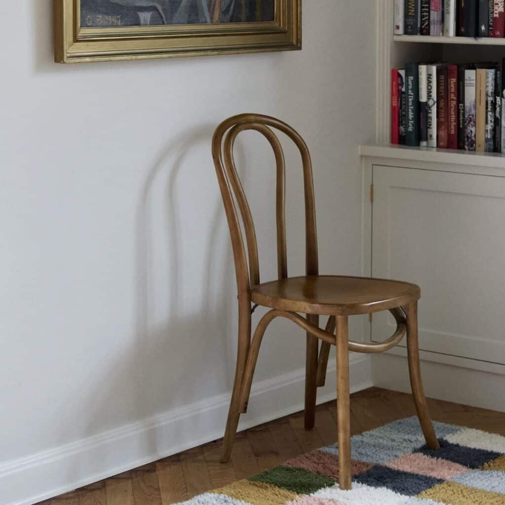 Bistrostol i björkträ i klassisk design placerad vid bokhylla i vardagsrum