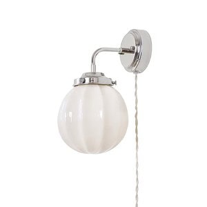 Vägglampa Marit från Strömshaga med förnicklad metall och rund opalglas kupa, beige textilsladd, sedd från sidan.