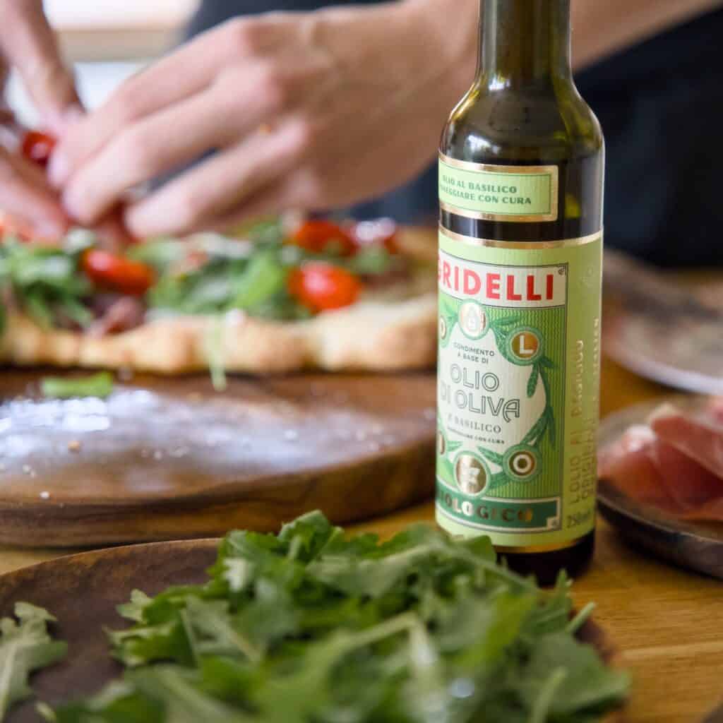 Gridelli Olivolja med smak av basilika 250 ml på bord med sallad och pizza - ekologisk extra jungfruolivolja