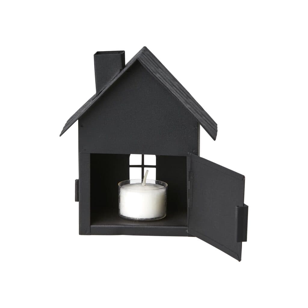 Svart ljuslykta i form av ett hus med öppna dörrar och ett tänd värmeljus inuti.