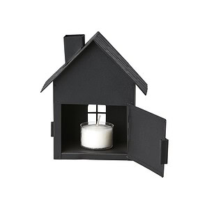 Svart ljuslykta i form av ett hus med öppna dörrar och ett tänd värmeljus inuti.