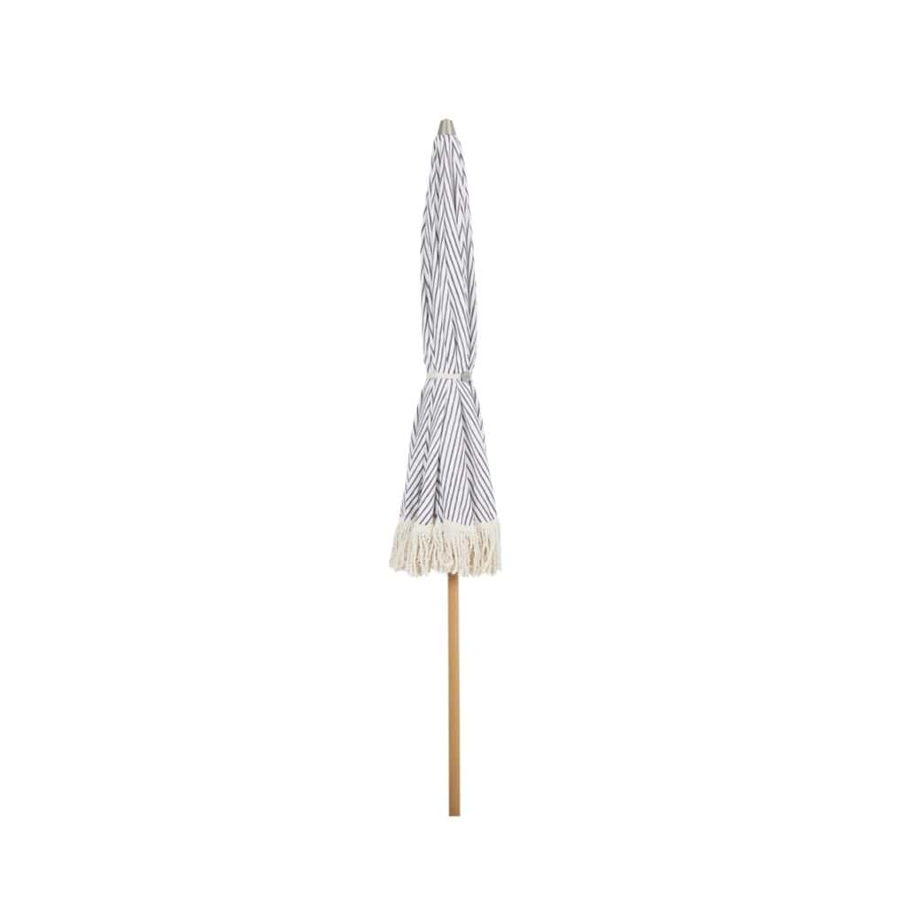 Ihopfällt Gatsby parasoll från Brafab med grårandigt tyg och dekorativa fransar, monterat på en trästång.