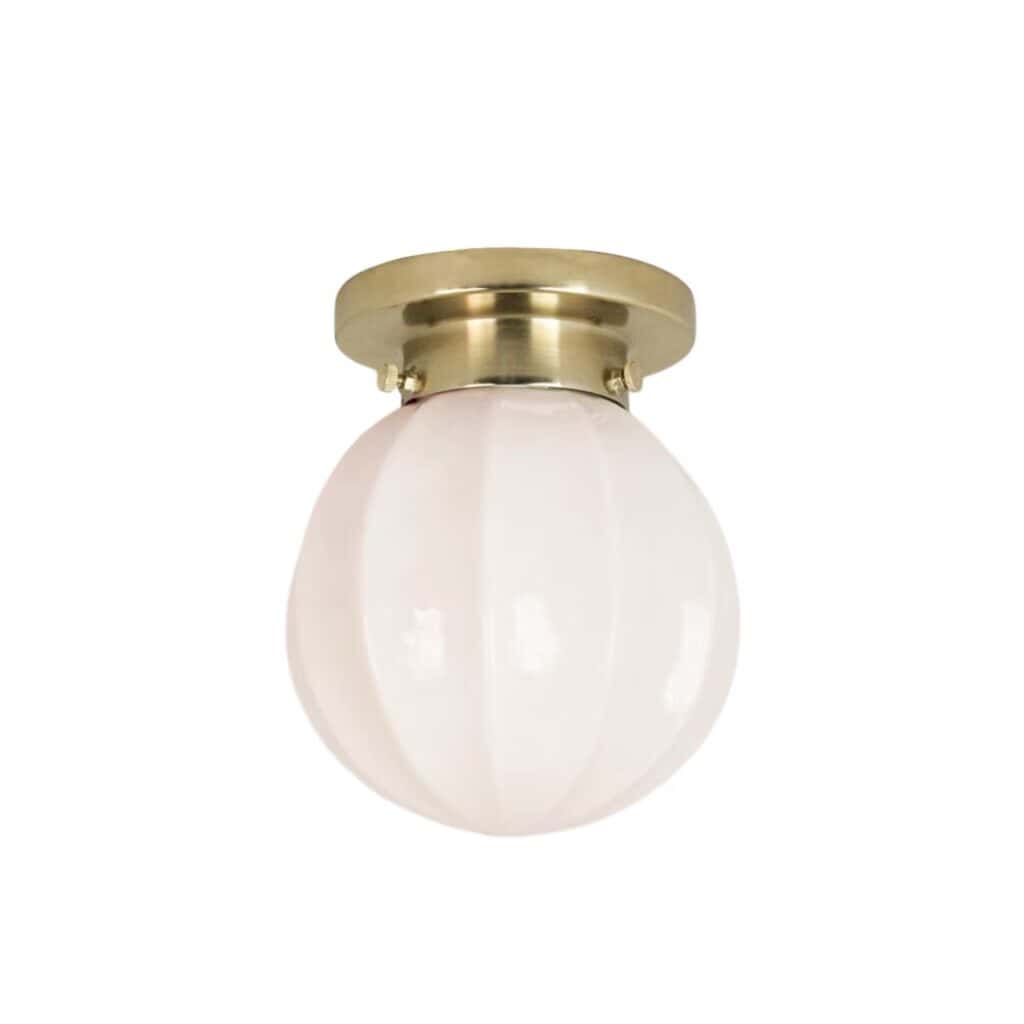 Elegant badrumslampa med mässingsfinish och munblåst opalglas i beige, monterad på en rund bas. Perfekt för klassiska och moderna badrum.