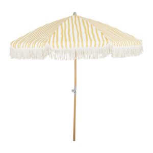 Gulrandigt parasoll Gatsby från Brafab med fransdetaljer och lutningsbar funktion, stående på en naturlig trästång.