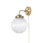 Vägglampa Eivor Mässing/Klar – en stilren lampa med mässingsfäste och räfflad glaskupa som ger ett mjukt och behagligt ljus. Perfekt för hallen, sovrummet eller vardagsrummet.