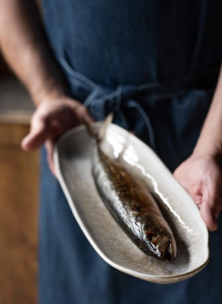 Ugnsbakad fisk på keramikfat – inspiration för sommarstugeinredning och matlagning nära naturen.