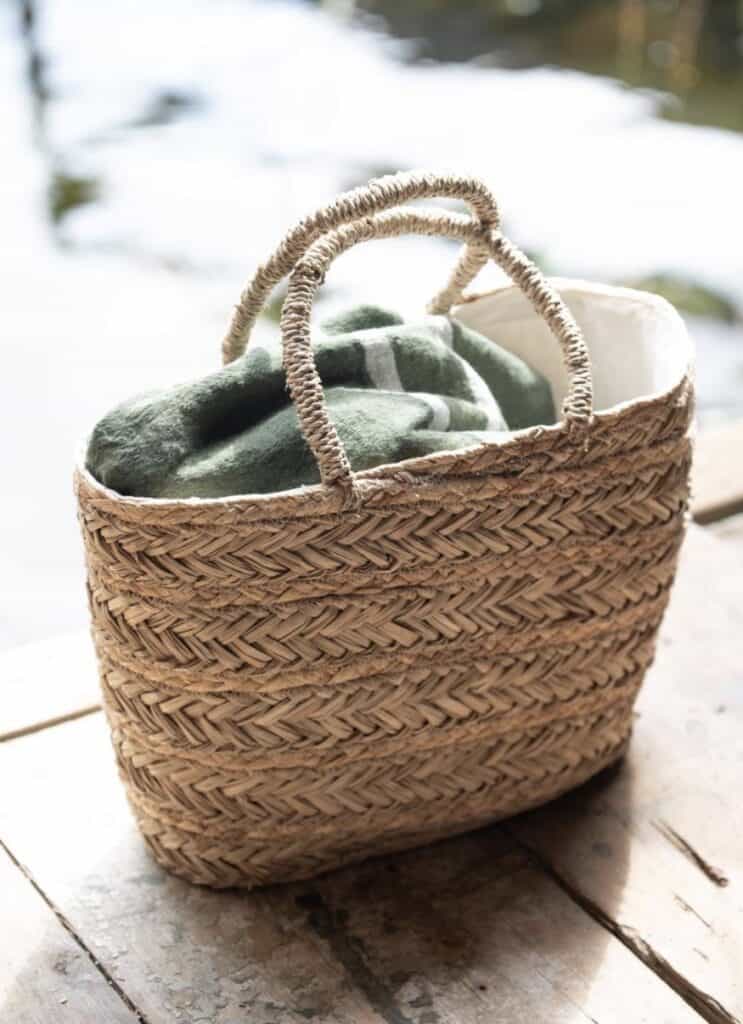 Flätad korg med grön filt – inspiration för sommarstugeinredning med funktionella naturmaterial.
