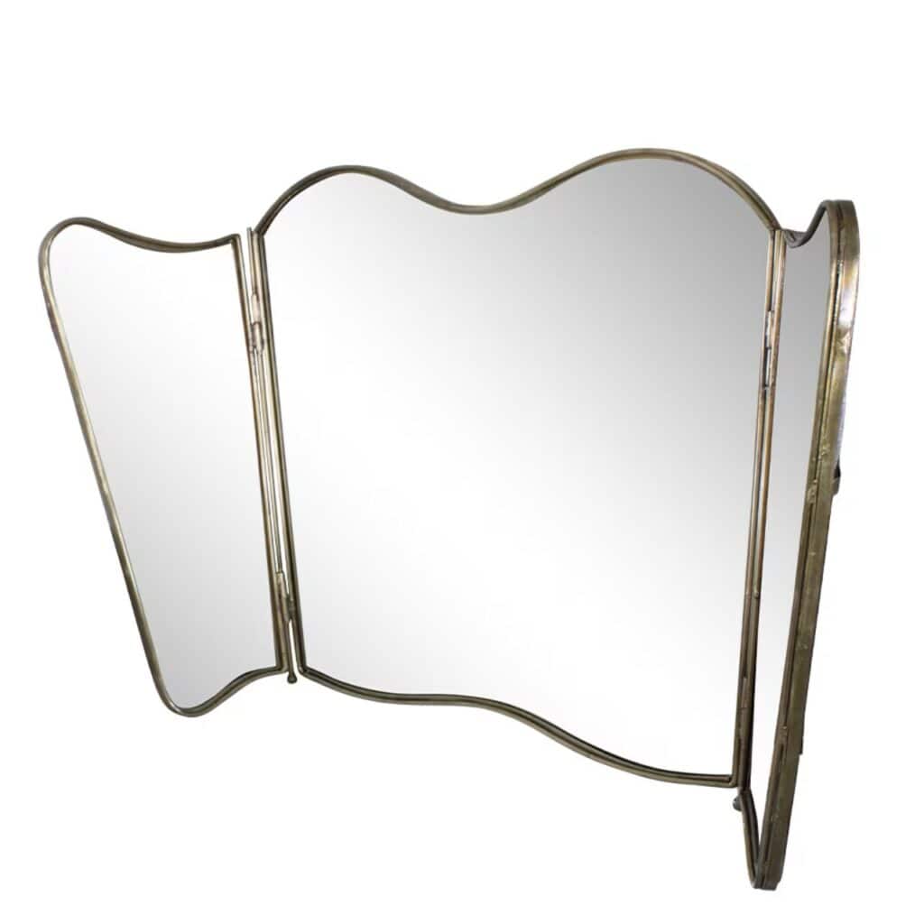 Tredelad vikbar spegel i antik mässing med vågig kant från Strömshaga. Sidospeglarna kan fällas in för flexibel användning och elegant vintagekänsla.