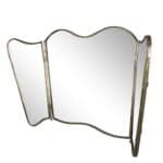 Tredelad vikbar spegel i antik mässing med vågig kant från Strömshaga. Sidospeglarna kan fällas in för flexibel användning och elegant vintagekänsla.