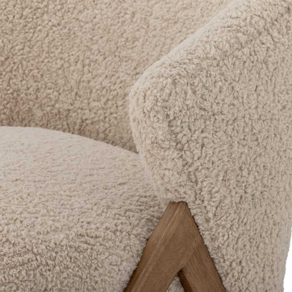Närbild på Camino fåtölj i beige teddyklädsel från Bloomingville med ben i mörk rubberwood.