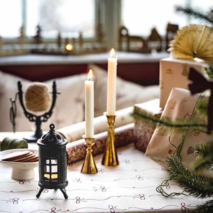 Kamin för värmeljus gjutjärn från Strömshaga på juldukad bord med tända ljus och paket