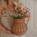 Person håller vas i rotting fylld med blommor