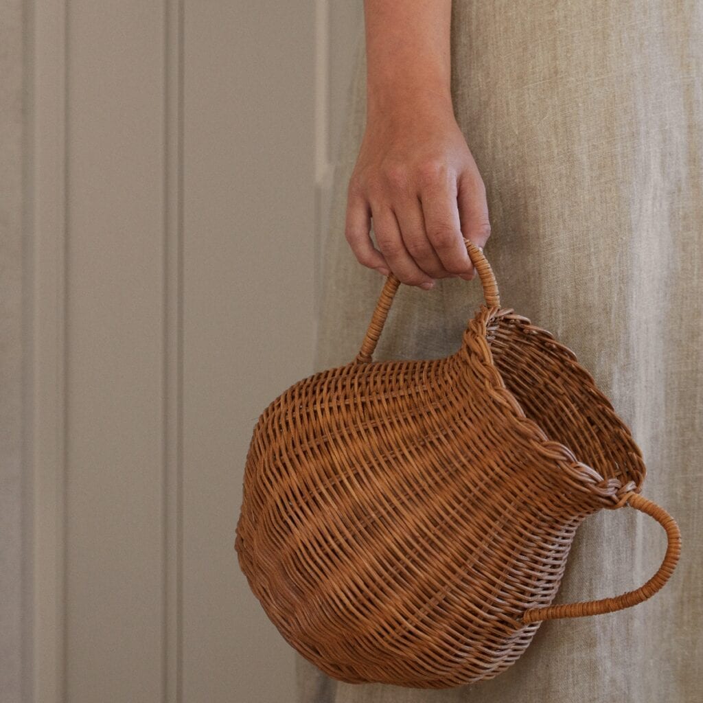 Hand som håller i vas i handflätad rotting med två handtag