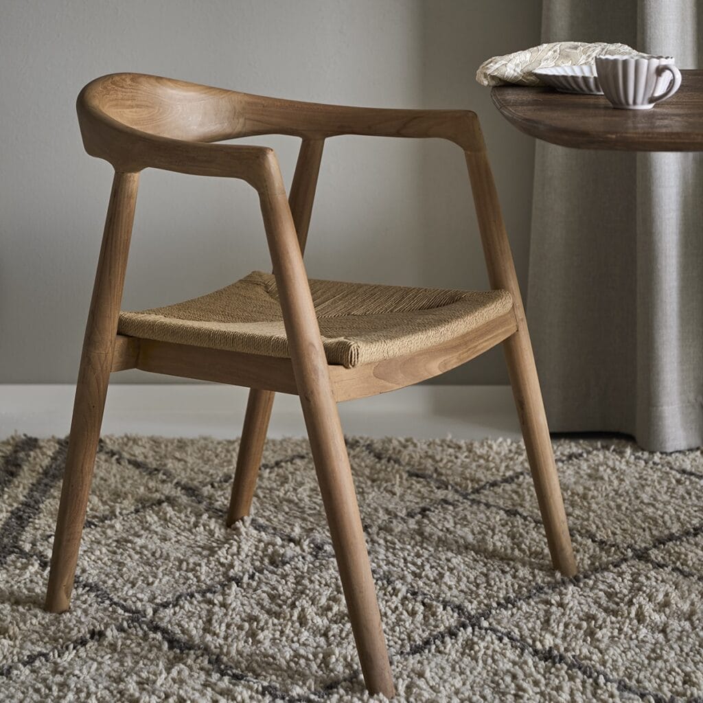 Portland karmstol i teak med flätad sits i rep, placerad vid bord i lugn miljö
