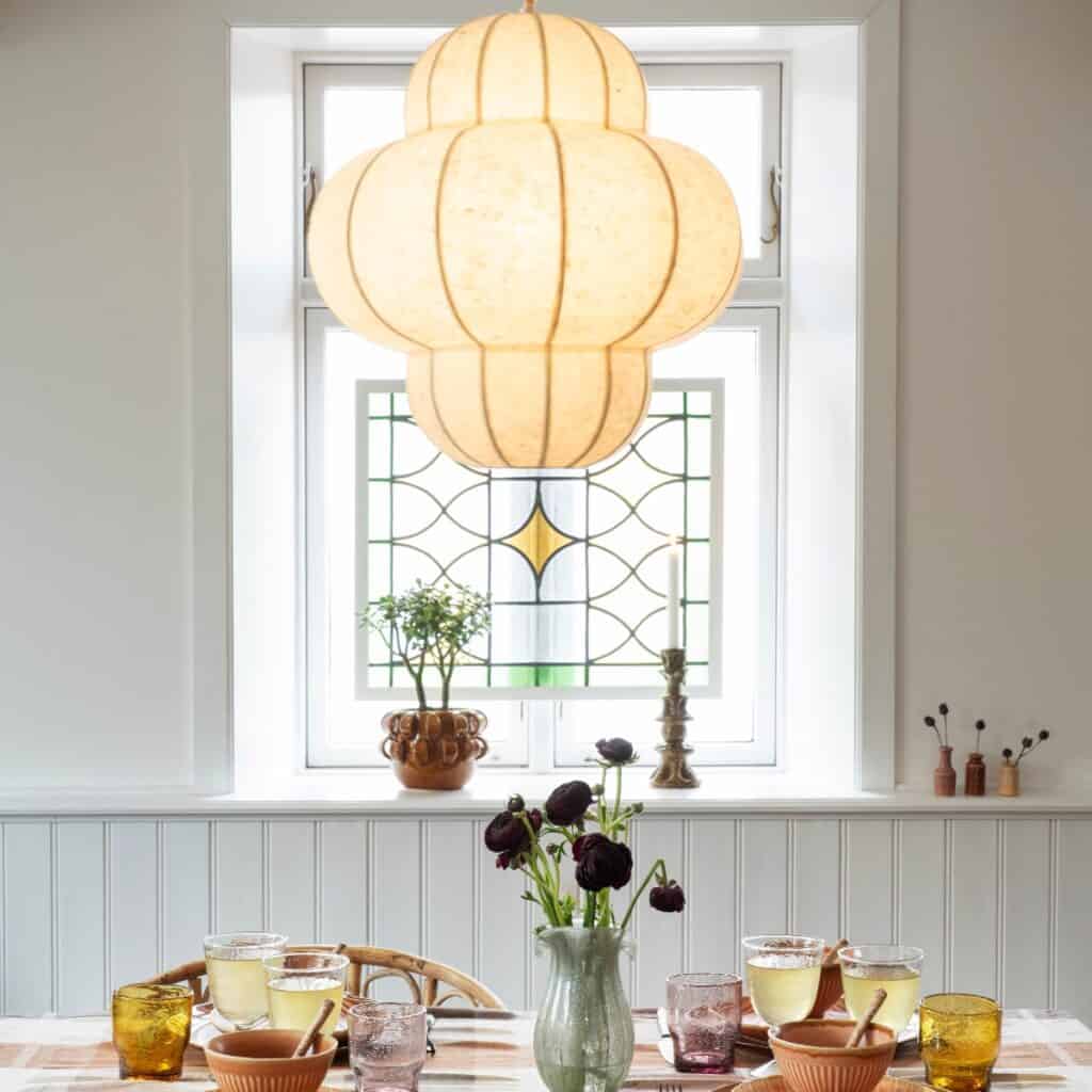 Tänd skulptural taklampa i offwhite över ett dukat matbord