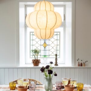 Tänd skulptural taklampa i offwhite över ett dukat matbord